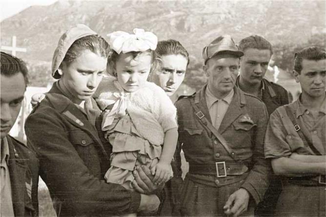 Châtillon (Champ-de-Cort), giugno 1945. Esumazione della salma del capo della banda della Suelvaz Émile Lexert “Milò” dal vecchio cimitero. Al centro il partigiano Mario Minuzzo “Alpino” con in braccio la figlia di Milò Renata Lexert. © Regione autonoma Valle d'Aosta - Foto Octave Bérard (fondo Bérard)